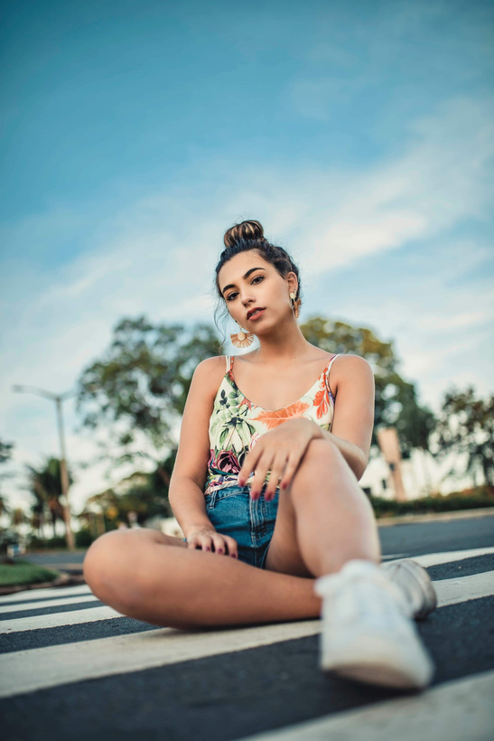 Woman in a White Top Seated at a Pedestrian Crossing